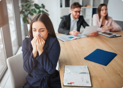 woman blowing nose at the office