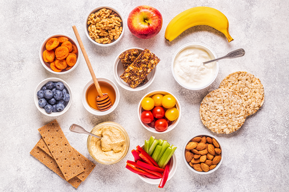 <p>A variety of healthy snacks for diabetics, including fruits, vegetables, nuts and whole-wheat crackers, in little containers.</p>