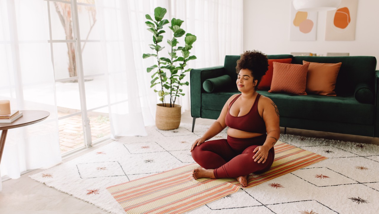 <p>A smiling woman practices meditation as part of a daily self-care checklist</p>