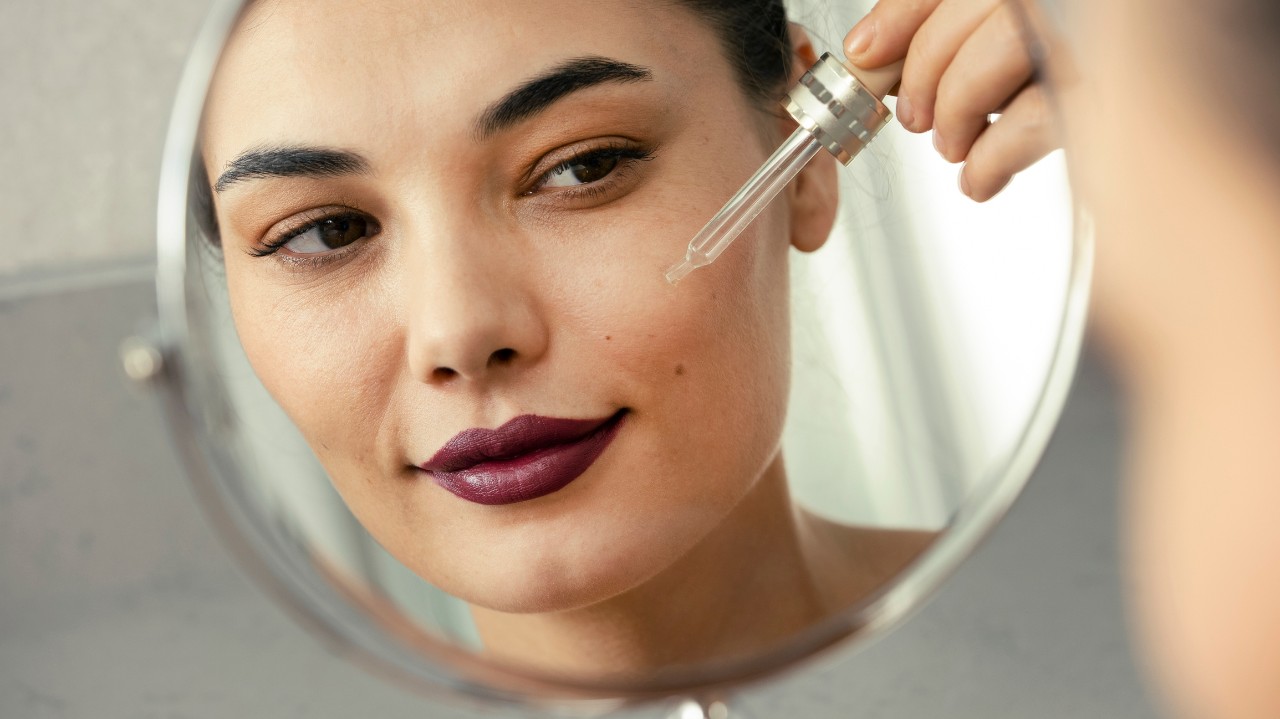 Woman applying serum to her clean face skin against a face wrinkles